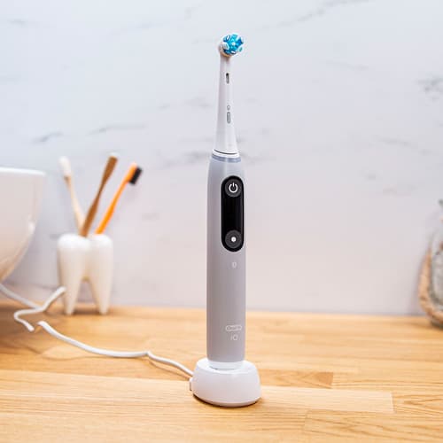 Grå Oral-B iO Series 6 med borsthuvud, stående på laddare.